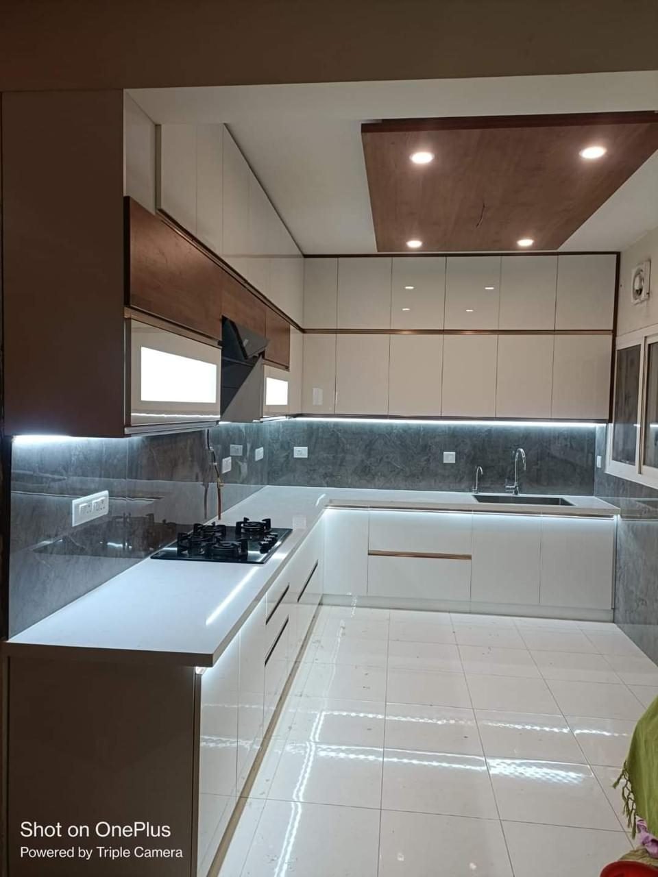 White modular kitchen with wood ceiling accent, Vadodara interior